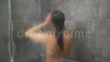 女人在淋浴时洗头发、肩膀、手臂和背部。 护发、美容和福利概念